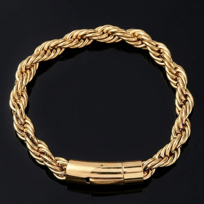A gold rope chain bracelet with a polished cylindrical clasp, displayed on a reflective black surface.