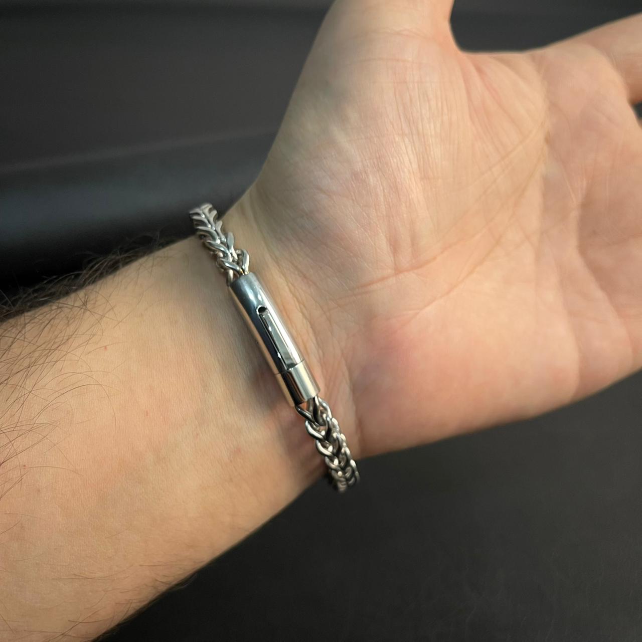 Silver bracelet on a wrist against a dark background