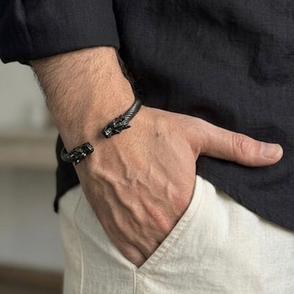 Hand wearing a black bracelet with a blurred background