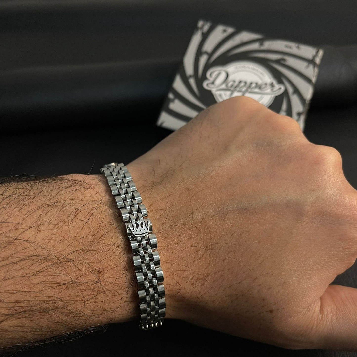 Hand wearing a silver bracelet with a black and white patterned pillow in the background