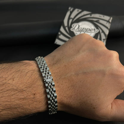 Hand wearing a silver bracelet with a black and white patterned pillow in the background