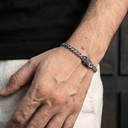 Hand wearing a silver chain bracelet with a blurred background