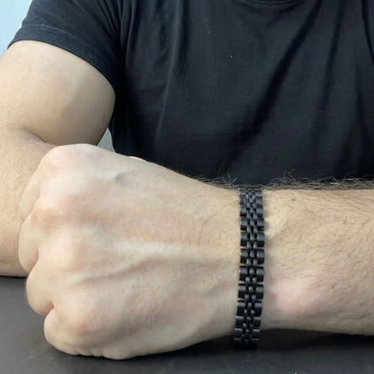 Person wearing a black braided bracelet on a neutral background