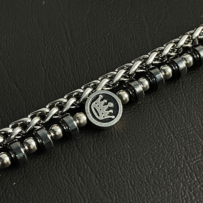 Silver chain bracelet with a crown emblem on a dark textured background