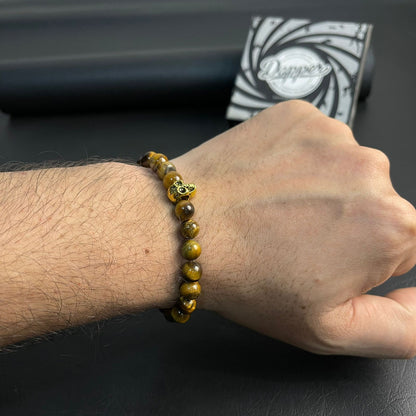 Person wearing a beaded bracelet on a dark surface with a branded box in the background
