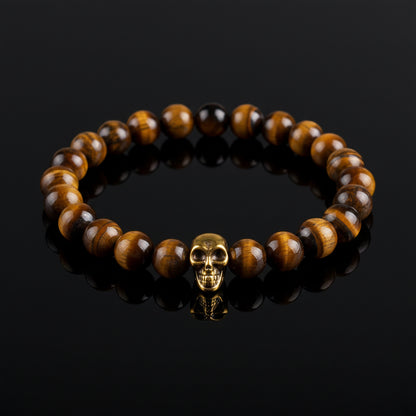 A Tiger Eye bead bracelet with golden skull detailing on a white background
